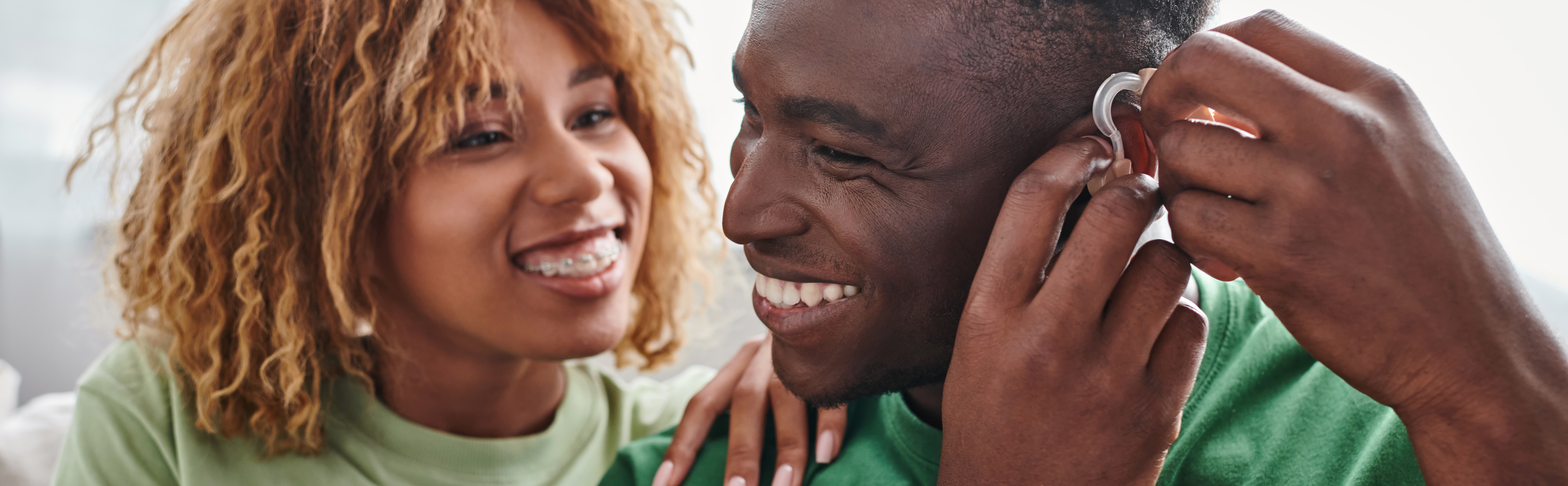 deaf and happy african american man wearing hearing aid near girlfriend, health device banner